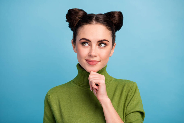 Closeup photo of attractive lady two funny buns good mood look side up empty space think creative idea arm on chin wear warm green turtleneck pullover isolated blue color background - Photo, image