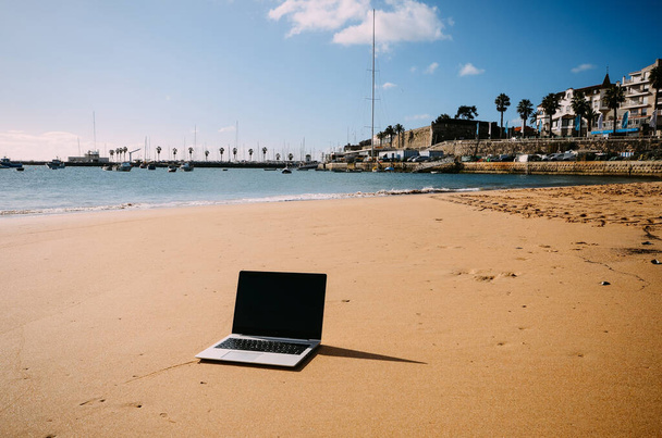 Yleinen kannettava tietokone aurinkoisella hiekkarannalla takana. Paradise home-office käsite erityisesti aikana Coronavirus Covid-19 puhkeaminen
 - Valokuva, kuva
