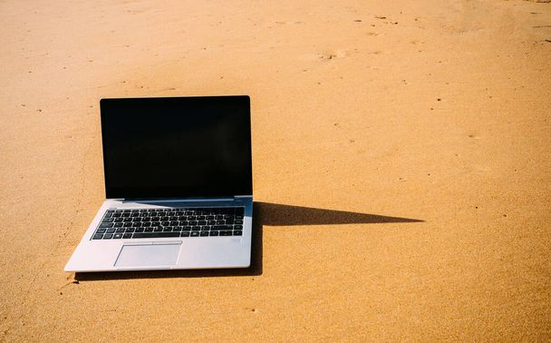 Portátil portátil genérico en soleado desierto fondo de playa de arena. Concepto de oficina en el hogar de Paradise, especialmente durante el brote de Coronavirus Covid-19
 - Foto, imagen