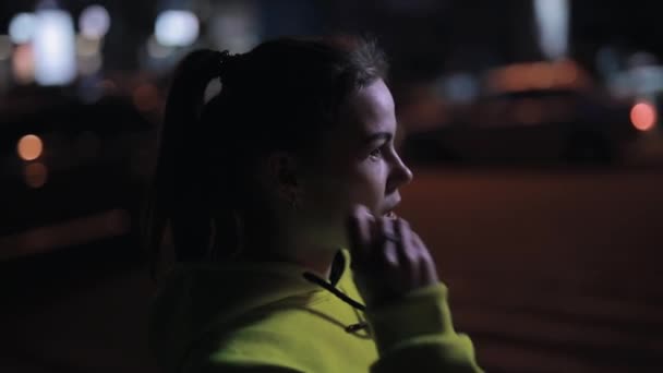 Pewna siebie sportowiec zakłada słuchawki bezprzewodowe w nocy - Materiał filmowy, wideo