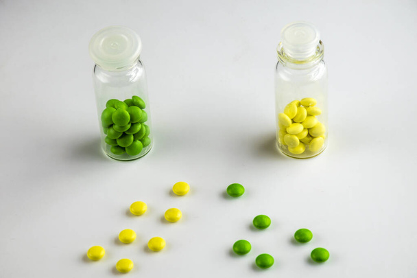 Multi-gekleurde pillen op een witte achtergrond, 2 capsules met pillen. - Foto, afbeelding