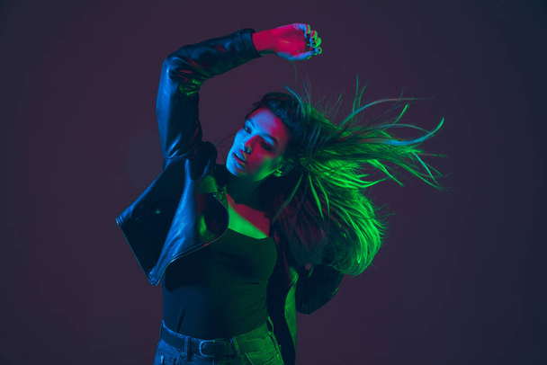 Beautiful womans portrait with blowing hair on dark studio background in colorful neon light - 写真・画像