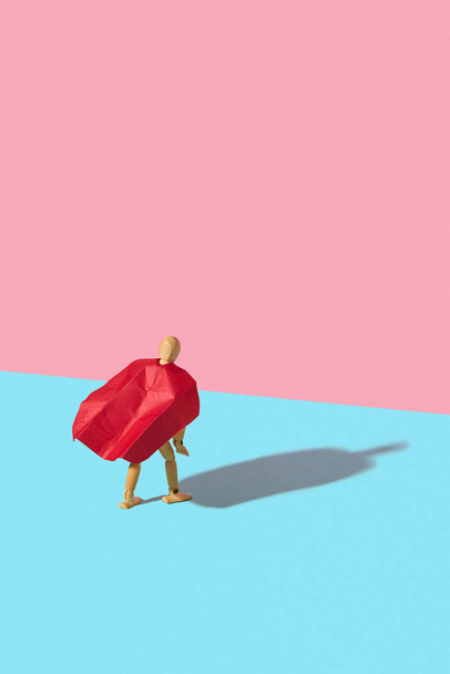 Movable human miniature model in red cape as a superhero or superman is standing on a duotone background with hard shadows, copy space. Business success and leadeship concept. - Foto, Imagen
