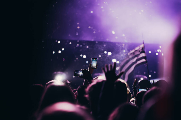 Luzes de palco e multidão de público com as mãos levantadas em um festival de música. Fãs curtindo as vibrações de festa
. - Foto, Imagem