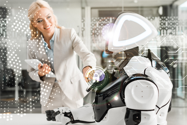 улыбающаяся деловая женщина, работающая роботом, держа в руках цифровой планшет, иллюстрация кибербезопасности
 - Фото, изображение