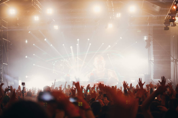 Φώτα σκηνής και πλήθος κοινού με χέρια σηκωμένα σε μουσικό φεστιβάλ. Θαυμαστές απολαμβάνοντας τις δονήσεις κόμμα. - Φωτογραφία, εικόνα