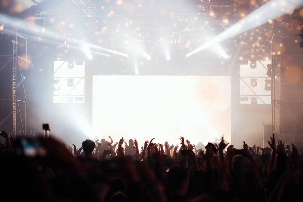 Lumières de scène et foule avec les mains levées lors d'un festival de musique. Les fans apprécient les vibrations de la fête
. - Photo, image