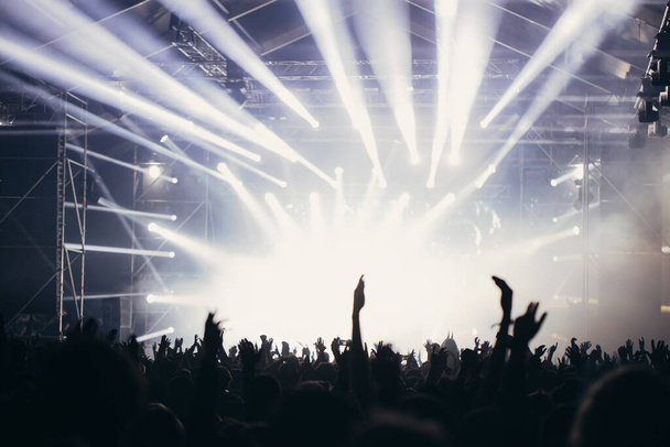 Сценические огни и толпа зрителей с поднятыми руками на музыкальном фестивале. Фанаты наслаждаются вечеринками
. - Фото, изображение