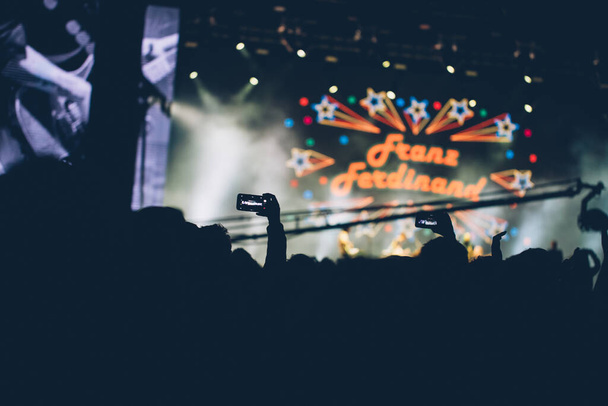 Luces de escenario y multitud de espectadores con las manos levantadas en un festival de música. Los fans disfrutando de las vibraciones de la fiesta
. - Foto, imagen