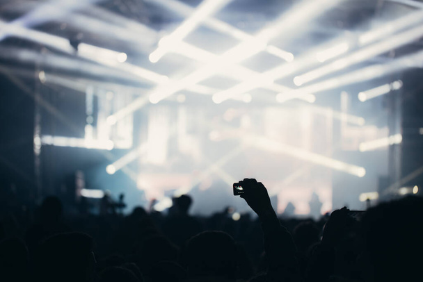Luces de escenario y multitud de espectadores con las manos levantadas en un festival de música. Los fans disfrutando de las vibraciones de la fiesta
. - Foto, Imagen
