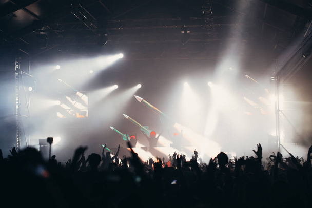 Сценічні вогні та натовп аудиторії з піднятими руками на музичному фестивалі. Вболівальники насолоджуються вечіркою
. - Фото, зображення