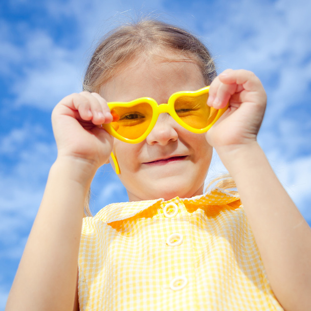 Portrait of a happy girl with sunglasses against the sky - Foto, afbeelding