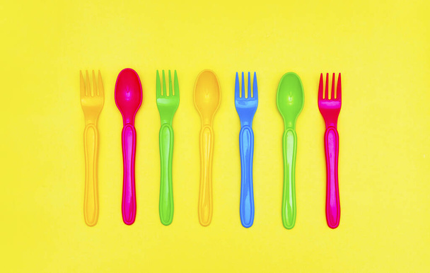 Vista dall'alto di cucchiaio colorato ed elemento forcella sul tavolo di colore giallo.flat lay design
. - Foto, immagini