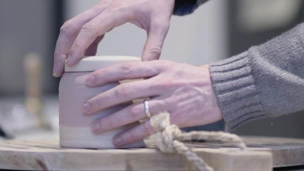 Man opent keramische pot en trekt theezakje en plaatst het in mok voor thee. Potje en mok zitten op grote houten uithangbord. - Video