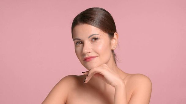 30s brunetka kobieta nosi decollete top z idealną skórą w studio na różowym tle - Zdjęcie, obraz