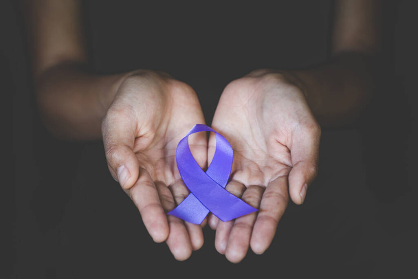 Hands holding Purple ribbons,  Pancreatic cancer, Epilepsy awareness, domestic violence awareness, Alzheimer disease, fibromyalgia awareness, world cancer day - Foto, imagen
