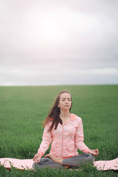 Het meisje in yoga op de outdoor in een veld - Foto, afbeelding