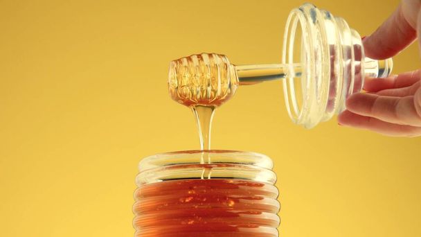 closeup of woman hand hold honey spoon with pouring honey - Fotoğraf, Görsel
