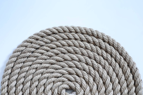Плетемо товсту мотузку, прив'язану до перекосу. Конопляна мотузка для прикраси та дизайну. Фон з рибальської мотузки
. - Фото, зображення