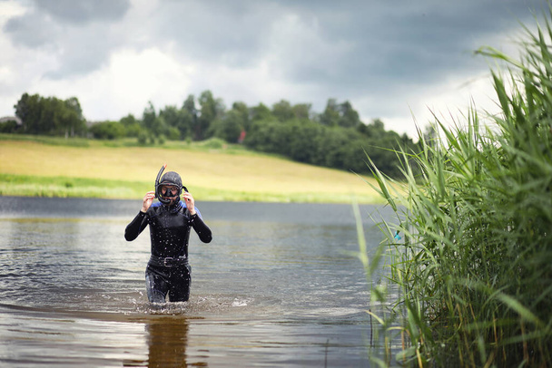 Um mergulhador em um terno molhado se prepara para mergulhar em uma lagoa - Foto, Imagem