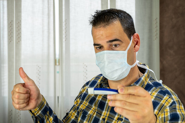 Hombre con máscara aliviado por tomar la temperatura corporal debido a covid-19
 - Foto, imagen