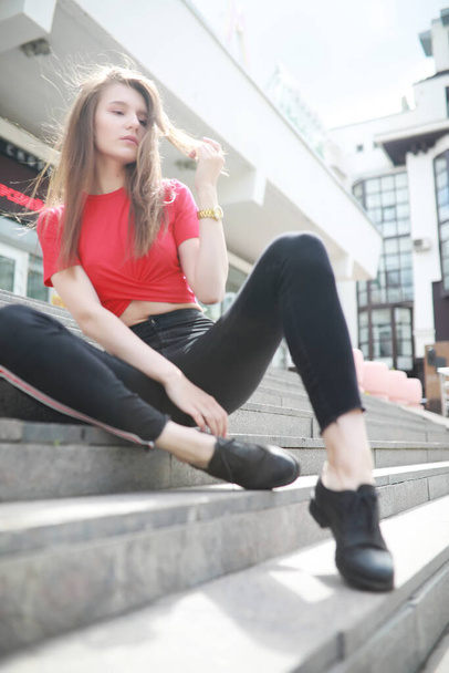 A girl posing on the steps of a building in sunny weathe - Zdjęcie, obraz