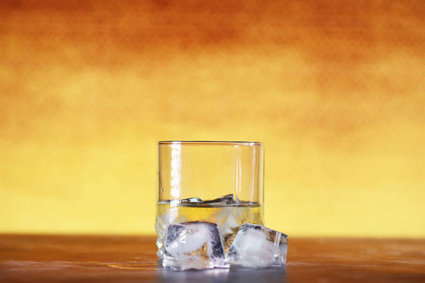Een glas harde alcohol met ijs op een bar. Whisky met frisdrank in glas. Reclame voor alcoholhoudende drank. - Foto, afbeelding