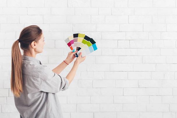 Νεαρή γυναίκα επιλέγει το χρώμα των τοίχων στο νέο δωμάτιο - Φωτογραφία, εικόνα