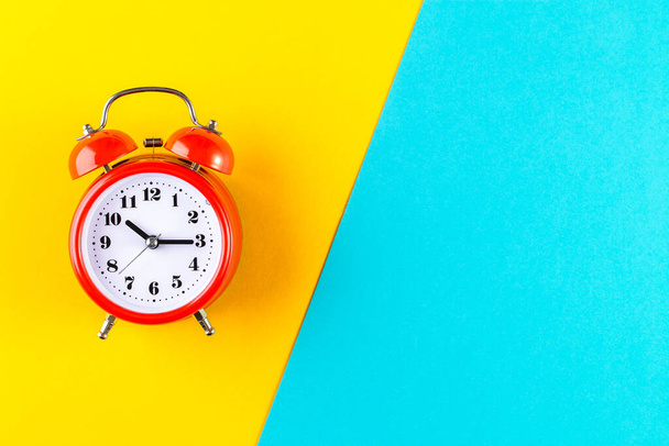 Red vintage alarm clock on a blue and yellow background. Time management concept - Фото, зображення