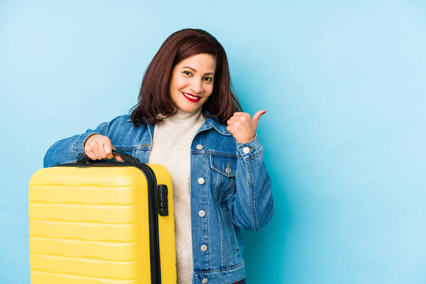 Keski-ikäinen latino matkustava nainen, jolla on matkalaukku eristetty hymyilevä ja nostamalla peukalo ylös
 - Valokuva, kuva