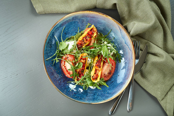 Close up view on Appetizing Italian caprese salad with fresh tomatoes, soft mozzarella, arugula and sauce in blue bowl rustic background. Healthy food - Foto, immagini