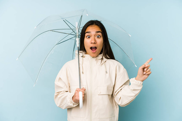 Giovane donna asiatica in possesso di un ombrello che punta al lato
 - Foto, immagini