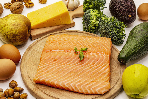 Trendy ketogene dieetproducten set. Vegetarische keto lage koolhydraten voeding. Vis, kaas, fruit en groenten. witte klei achtergrond, close up - Foto, afbeelding