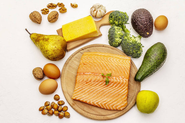 Set de productos dietéticos cetogénicos de moda. Alimentación vegetariana keto baja en carbohidratos. Pescado, queso, frutas y verduras. Fondo masilla blanca, vista superior
 - Foto, imagen
