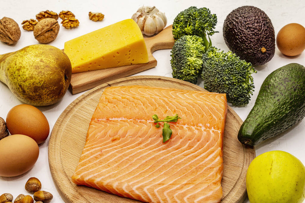 Set de productos dietéticos cetogénicos de moda. Alimentación vegetariana keto baja en carbohidratos. Pescado, queso, frutas y verduras. Fondo de masilla blanca, primer plano
 - Foto, imagen