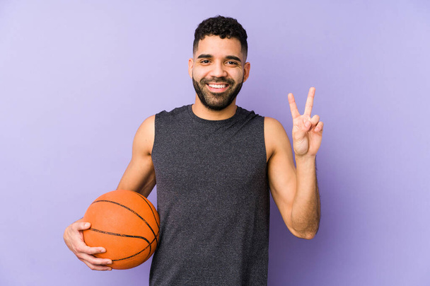 Young latin man playing basket isolated showing number two with fingers. - Foto, afbeelding