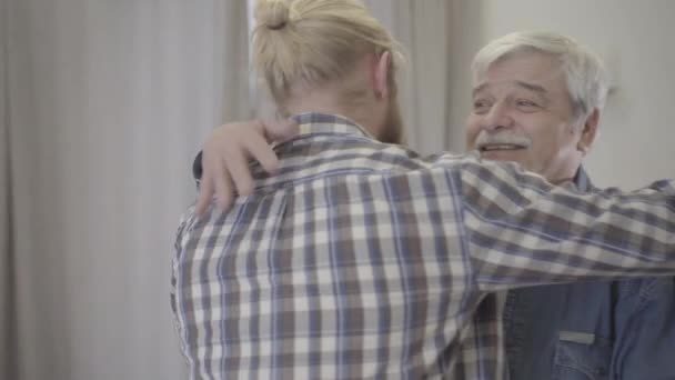 Close-up of happy elderly Caucasian man hugging adult son indoors. Portrait of smiling senior retiree glad with meeting. Family, lifestyle, unity, happiness. - Filmati, video