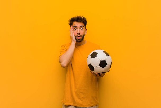 Young soccer player man surprised and shocked - Фото, изображение