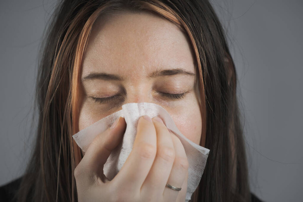Sneezing, coughing or blowing nose in a single use paper towl. Concept of catching cold, virus or infection and not spreading it - Foto, imagen
