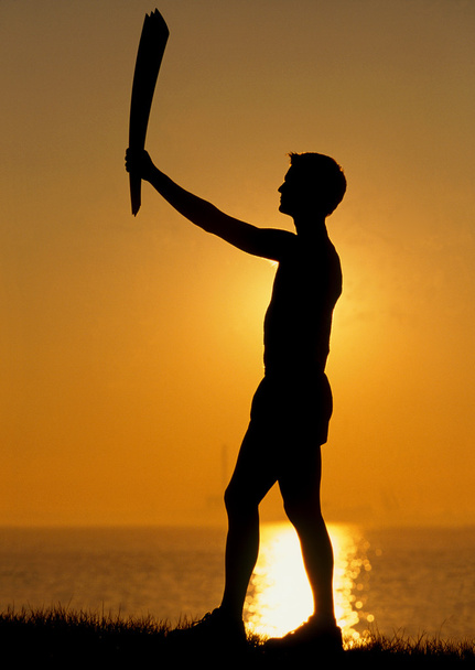 Silhouetted runner with an Olympic torch - Photo, Image