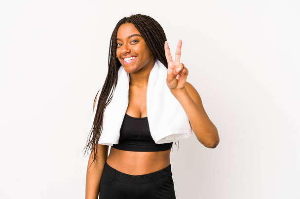 Jeune femme sportive afro-américaine isolée montrant un signe de victoire et souriant largement
. - Photo, image
