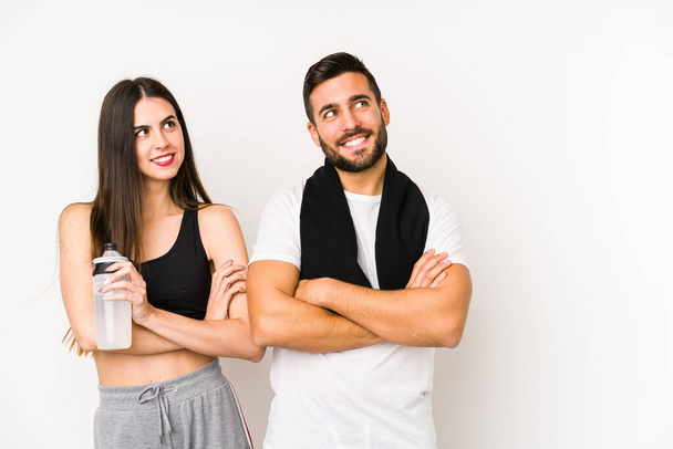 Young caucasian fitness couple isolated smiling confident with crossed arms. - Φωτογραφία, εικόνα