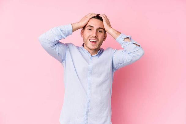 Young caucasian man posing in a pink background isolated laughs joyfully keeping hands on head. Happiness concept. - Fotografie, Obrázek
