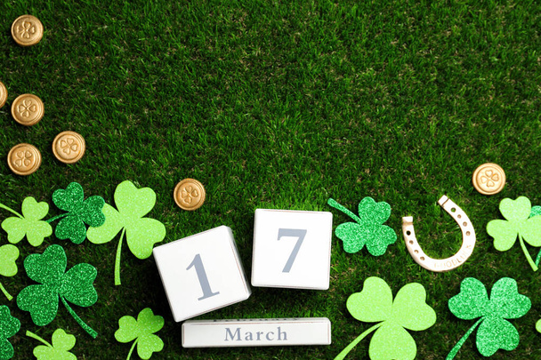 Flat lay composition with horseshoe and block calendar on grass, space for text. St. Patrick's Day celebration - Zdjęcie, obraz