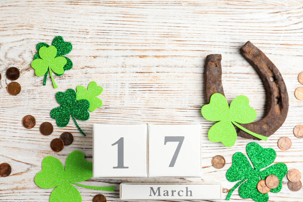 Flat lay composition with horseshoe and block calendar on white wooden background. St. Patrick's Day celebration - Φωτογραφία, εικόνα