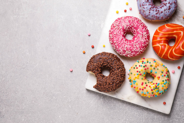 Yummy donuts with sprinkles on light grey table, top view. Space for text - Fotografie, Obrázek