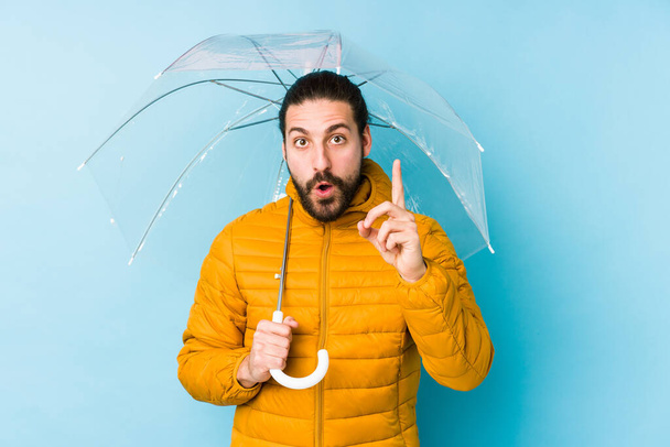 Młody człowiek z długimi włosami, trzymający odizolowany parasol z pomysłem, inspiracją.. - Zdjęcie, obraz