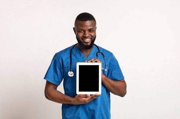 Médecin noir souriant démontrant écran de tablette numérique vide
 - Photo, image