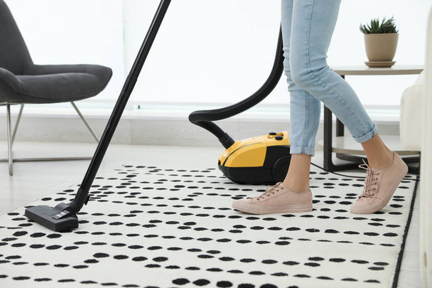 Young woman using vacuum cleaner at home, closeup - Foto, Imagen