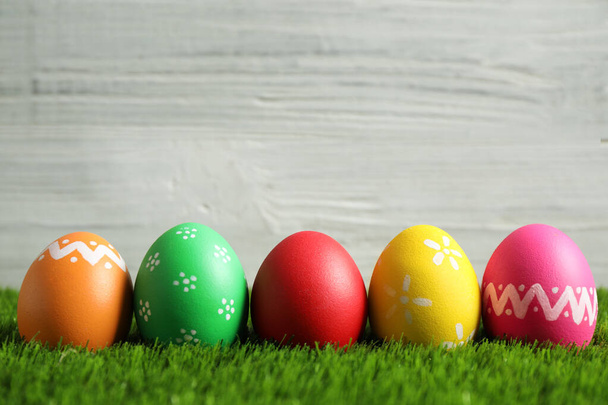 Colorful Easter eggs on green grass against white background. Space for text - Fotoğraf, Görsel